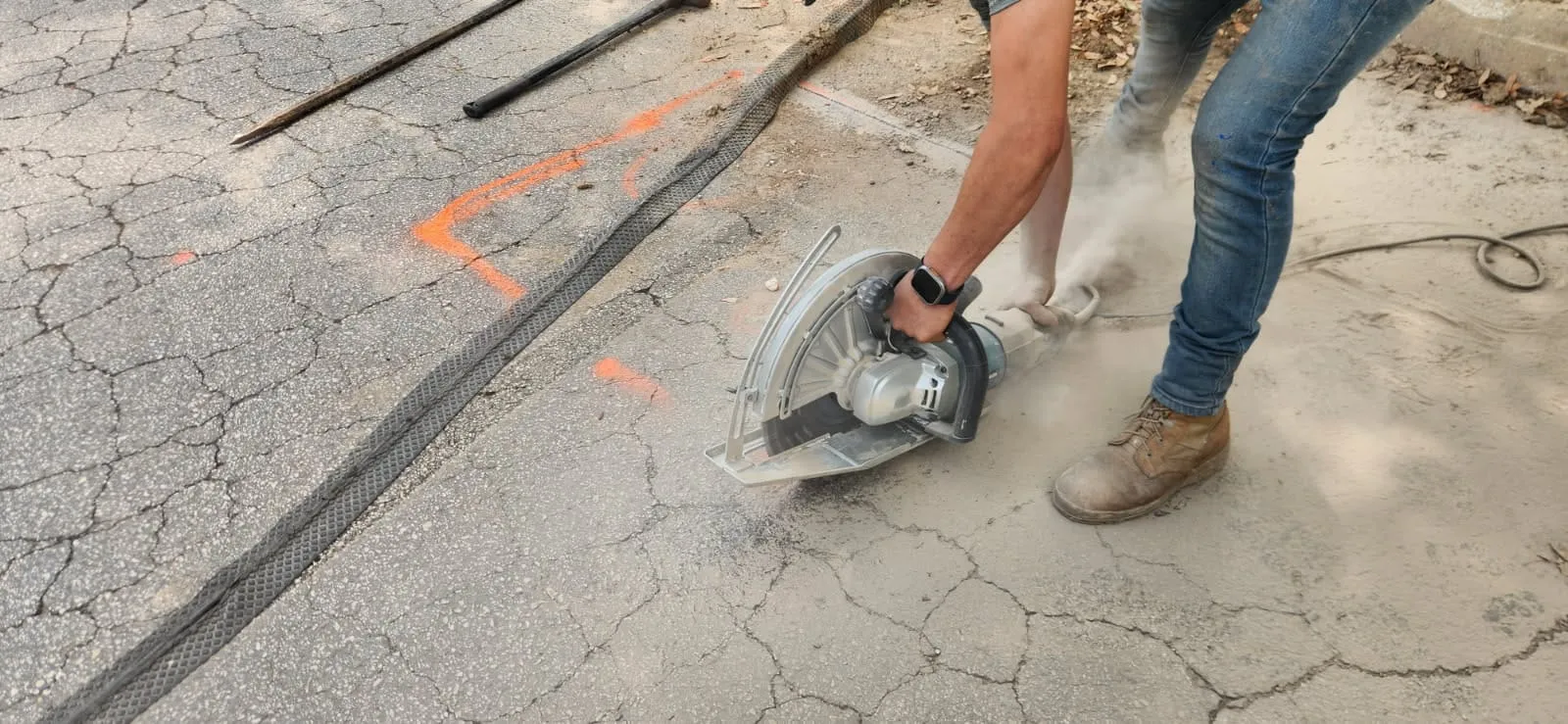 Crew member making a precise saw cut in concrete for hardscape installation