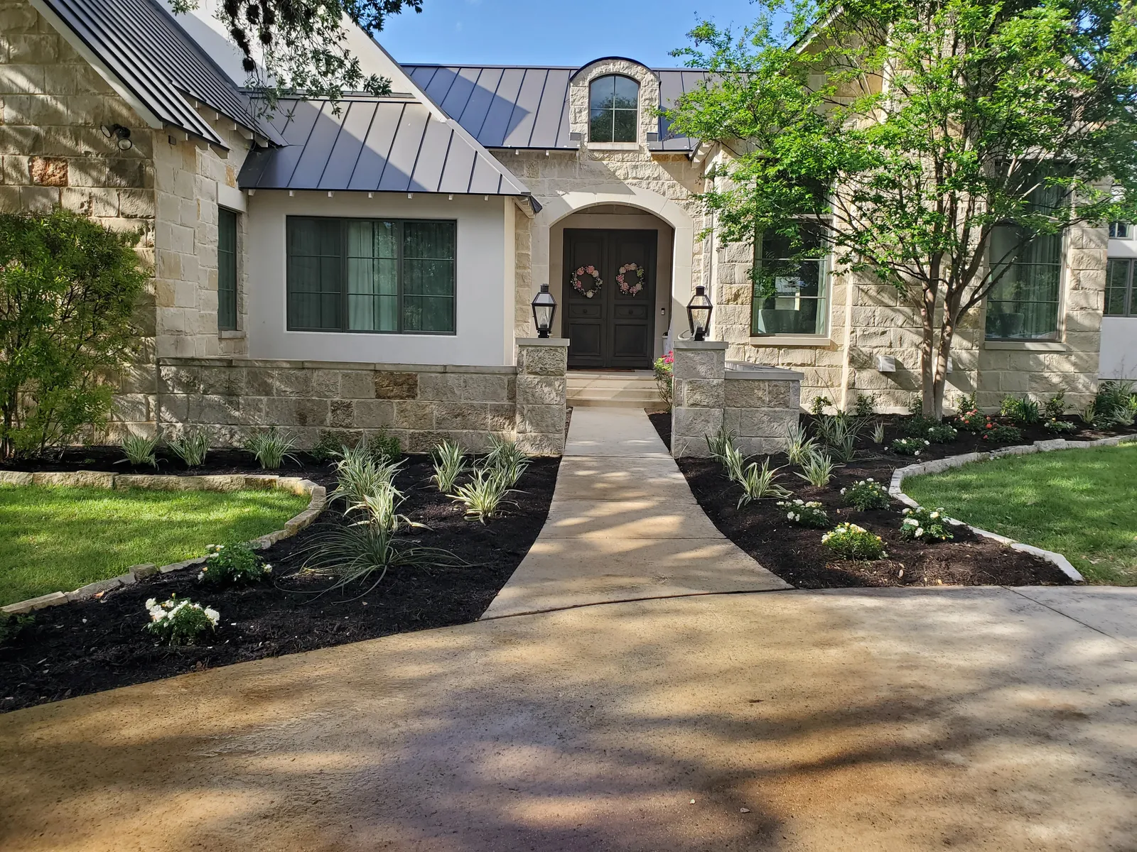 Freshly finished front landscape with curved beds and dark mulch